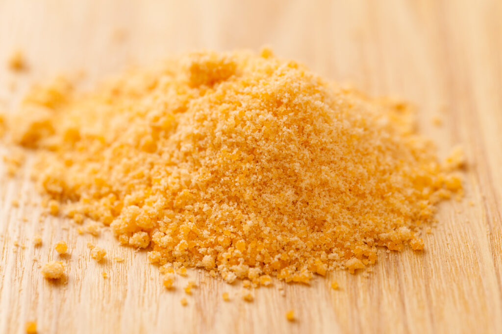 This image showcases a heap of golden brown raw sugar, known for its large granules and slightly less refined state, which provides a richer flavor than white sugar. The grains are spread across a light wooden background, emphasizing the sugar's natural, unrefined quality and its caramel-like color that hints at its deeper, molasses-infused taste. The texture and organic feel of the sugar are in the spotlight, suggesting its use in giving a robust flavor and a crunchy topping to desserts like crème brûlée.